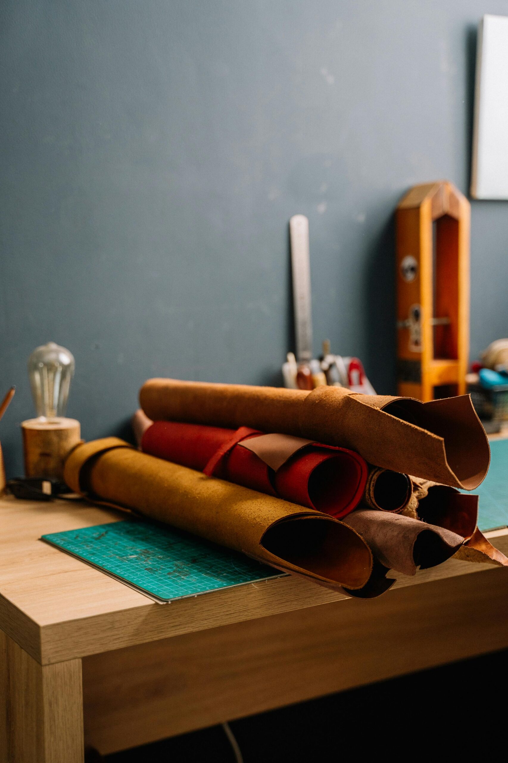 Vegetable-tanned leather rolls stacked on a craft workshop table — premium full-grain leather by Bulani India
